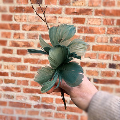 Grönblå fjäderblomma på en gren i påskriset.