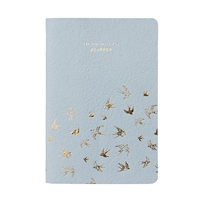 Ljusblå anteckningsbok med guldiga fåglar och en vacker text på framsidan.