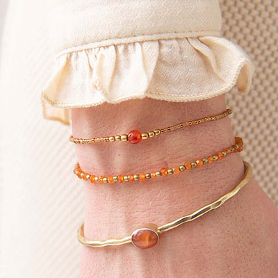 Flera armband i guld med den orange kristallen Karneol.