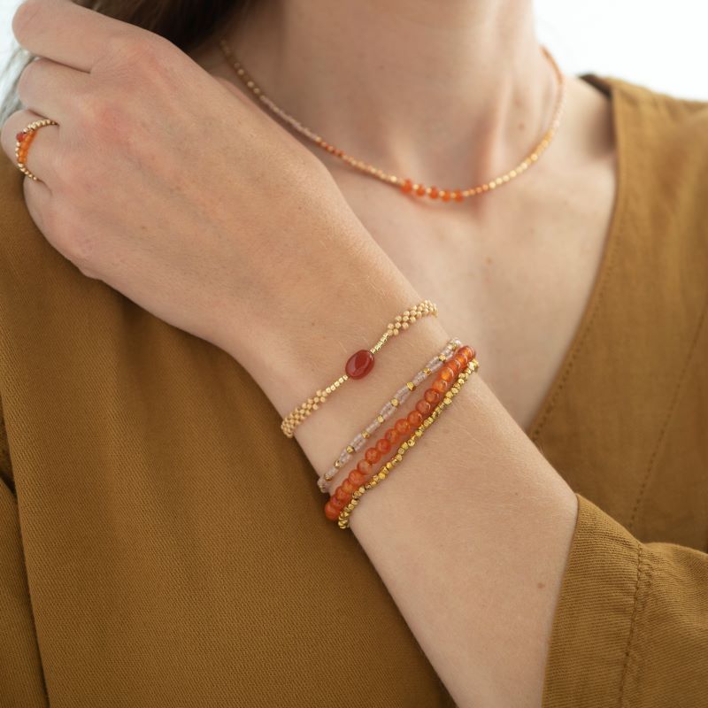 Armbandet Emotion med en Karneol och pärlor i glas och mässing som sitter på en kvinnas handled.