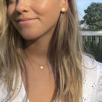 Halsband i guldplätering med fredstecken om en tjejs hals.