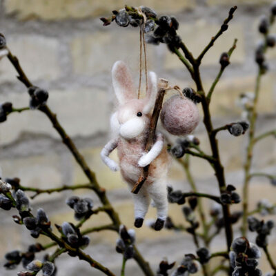 Söt liten kanin i tovad ull som hänger i en videkvist.