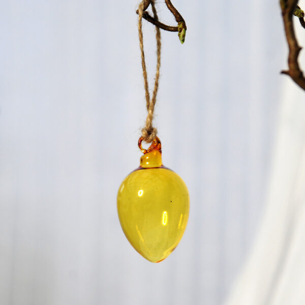 Munblåst glasägg i gult glas att hänga upp i påskriset.