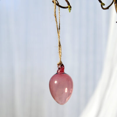 Munblåst glasägg i rosa glas att hänga upp i påskriset.