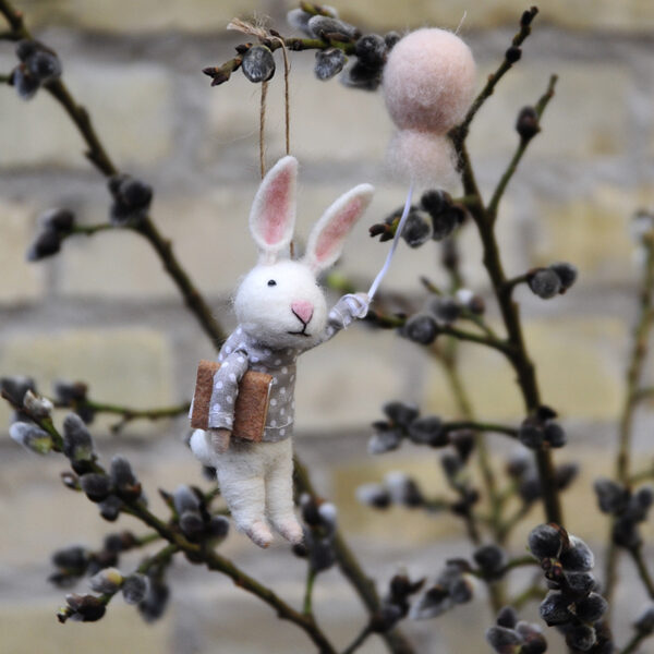 Söt liten kaninkille i tovad ull med en rosa ballong i handen.