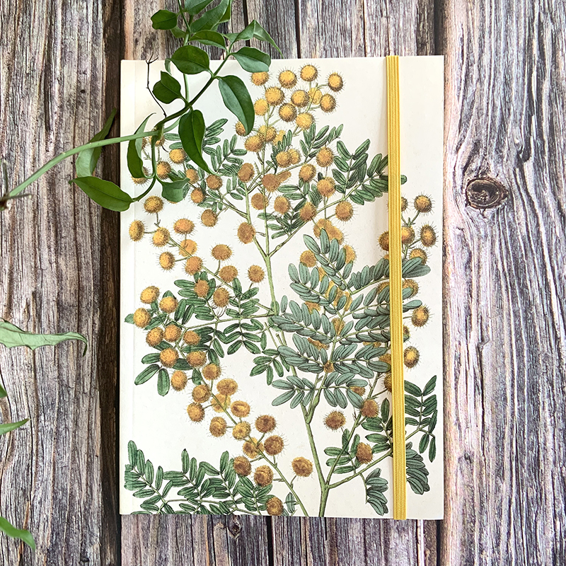 Anteckningsbok i A5 storlek från Sköna Ting med gula Mimosa-blommor på framsidan av pärmen.