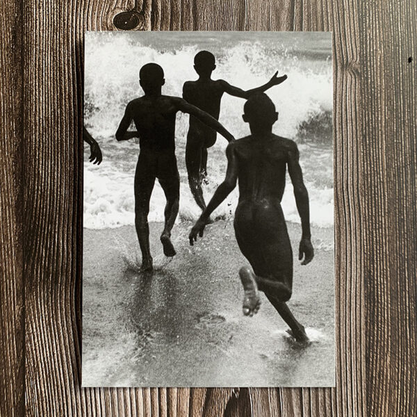 Svartvitt kort med motiv från 30-talet som föreställer personer som springer på en strand.
