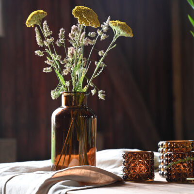 Brun glasflaska med blommor i.