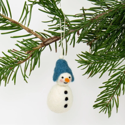 Julgranshänge i form av en tovad ullsnögubbe med blå mössa som hänger på en gren.