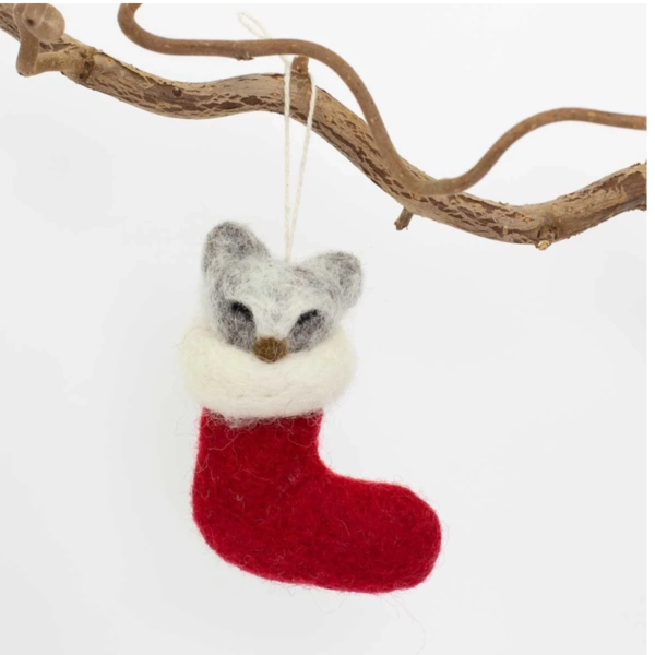 Julgranshänge i form av en tovad ulltvättbjörn som sitter i en röd julstrumpa som i sin tur hänger på en gren.