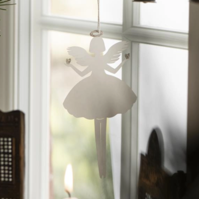 En ängel i vit papper med glittriga detaljer som hänger i ett fönster.