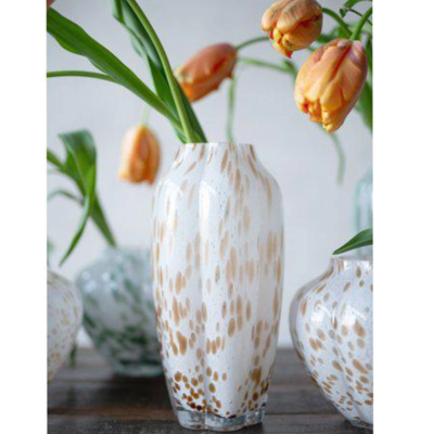 Hög vit glasvas med beige stänk med orange tulpan i.