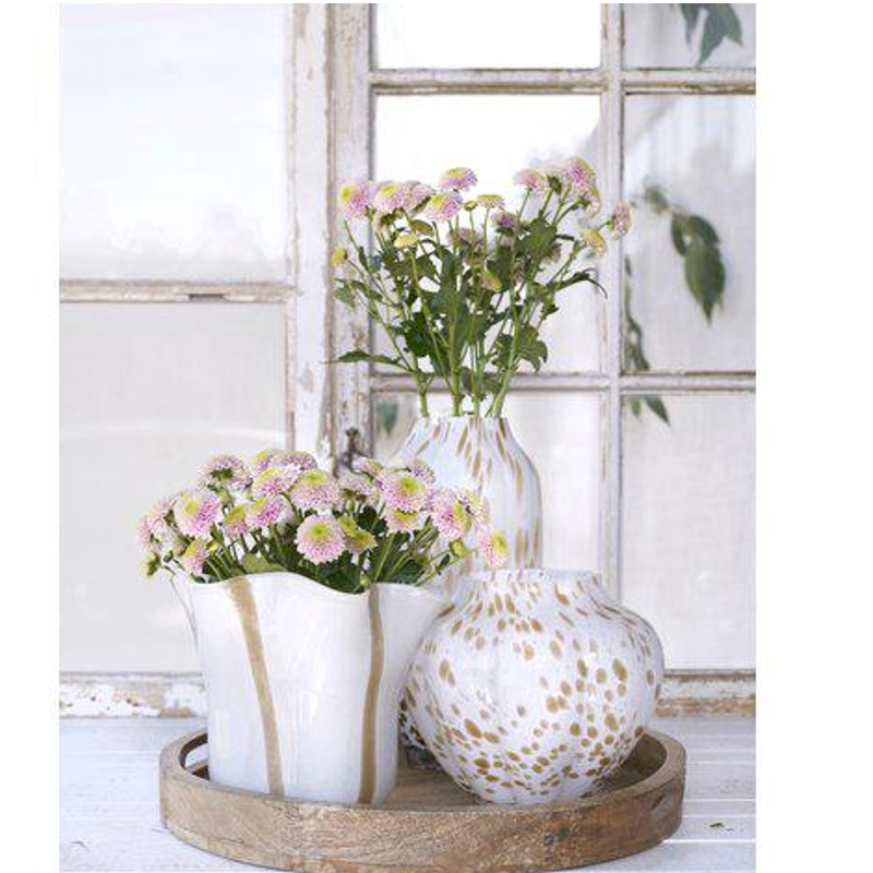 Tre vita glasvaser i olika storlekar med beige detaljer med blommor i, ståendes på en träbricka.