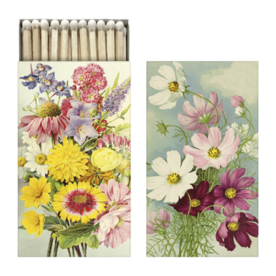 2 st tändsticksaskar med blommotiv på framsidan. På den enda asken ser man vita toppar tändstickor sticka upp.