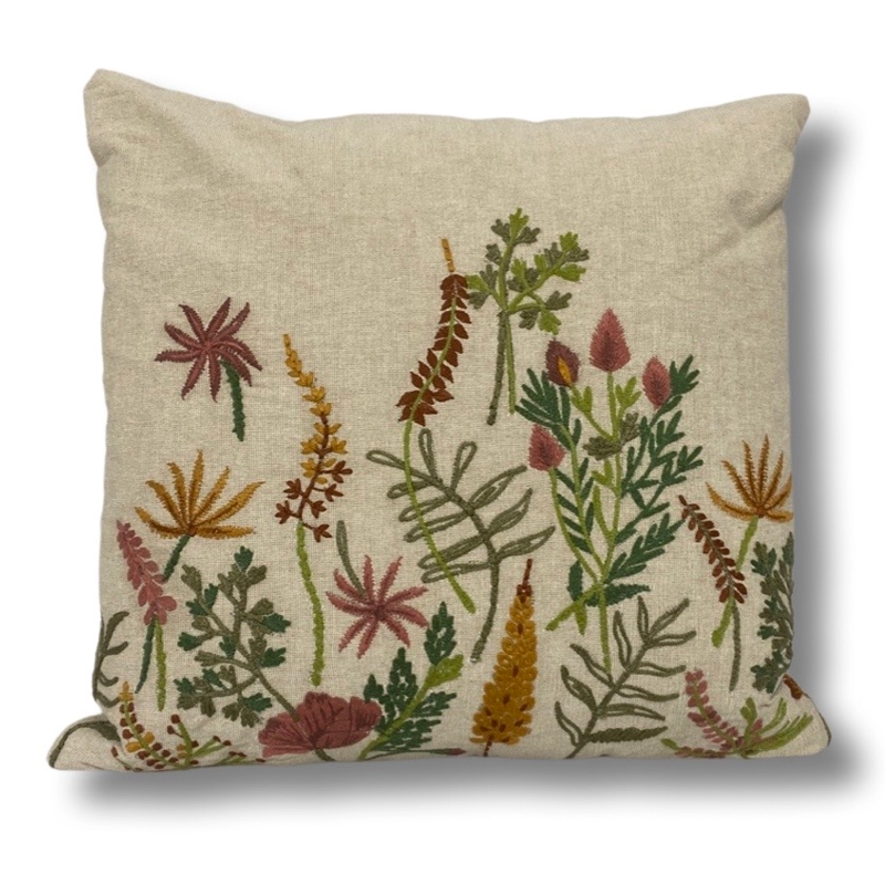 Prydnadskudde med broderad blommor på en beige botten.